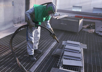 при дробеструйной обработке металла специалист надевает плотный защитный костюм